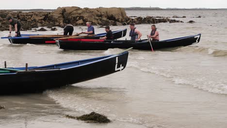 Currach-boat-racers-paddle-traditional-wooden-oars-to-shore-of-ladies-beach