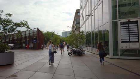 Gente-Caminando-Fuera-Del-Edificio-De-Oficinas-Contemporáneo-En-Eindhoven,-Países-Bajos