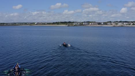 Blick-Richtung-Ladies-Beach-In-Galway,-Während-Die-Currach-Boote-Schnell-In-Richtung-Offenes-Meerwasser-Blicken