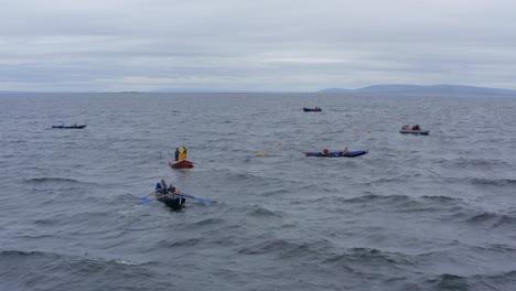 Aerial-overview-of-racing-Currach-boats-off-the-coast-on-cloudy-moody-day-by-ireland