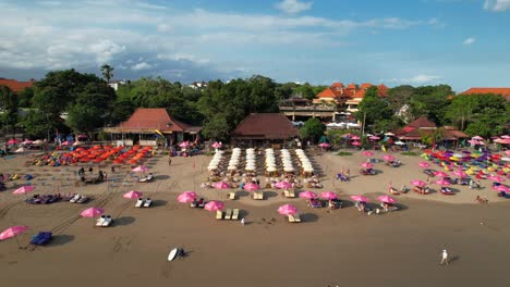 Double-Six-Beach-With-Many-Rental-Umbrellas-for-Suntanning---Aerial-Revealing-Push-Back-Shot,-Bali,-Indonesia