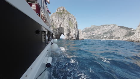 Day-time,-boat-trip-arrives-at-Faraglioni,-the-rock-with-the-hole