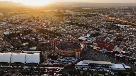Aerial-view-tilting-toward-the-Plaza-de-Toros-arena,-sunny-evening-in-Aguascalientes,-Mexico