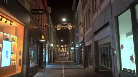 Empty-decorated-shopping-street-in-Maastricht-at-night-with-illuminated-shop-windows