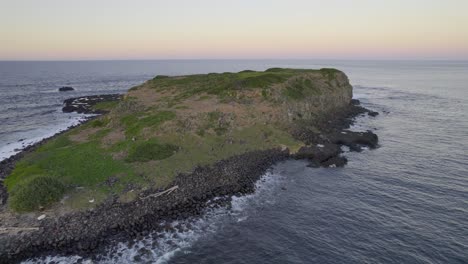 Cook-Island-With-Foamy-Ocean-Waves-Hitting-Rocky-Shore-At-Sunset-In-NSW,-Australia---drone-shot