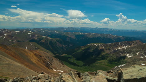 Cinematic-time-lapse-top-of-the-world-Grays-and-Torreys-14er-Rocky-Mountains-peaks-layers-Colorado-Breckenridge-landscape-in-background-sunny-summer-day-peaceful-blue-sky-clouds-rolling-snow-at-top