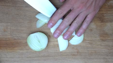 top-down-shot-of-a-medium-white-onion-being-cut-in-slices-with-a-chef-knife