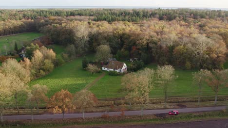 Side-panning-shot-of-country-house-near-forrest-at-Oudemirdum-Friesland,-aerial
