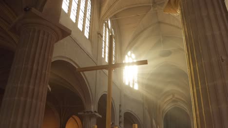 Bright-rays-of-sunlight-coming-through-a-church-window,-cross-below