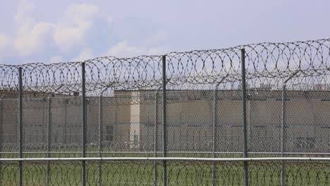 Huntsville-Prison-Unit-exterior-of-jail-in-Livingston-Texas-outside-fence-where-guards-patrol-with-razor-barbed-wire-fence-and-building-in-background-establishing-shot
