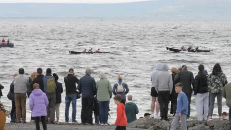 Onlookers-stand-on-seawall-watching-currach-boat-racing-in-galway-ireland