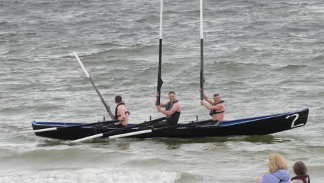 Currach-boat-racers-hold-up-wooden-painted-oars-after-winning-anniversary-race