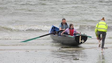 Support-crew-staff-adjust-currach-boat-as-father-attempts-to-push-off-into-ocean