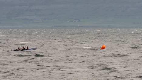 Static-shot-of-currach-boat-entering-galway-bay-with-county-clare-behind,-rounding-race-course-buoy