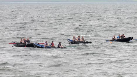 Slow-motion-pan-across-competitive-currach-boat-racers-in-galway-bay-sea