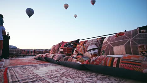 Tourists-on-the-roof-terrace-watching-the-balloons-floating-overhead-at-sunrise-in-Cappadocia
