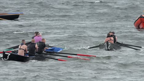Currach-boats-approach-the-shore,-rowing-backwards-to-ladies-beach-ireland
