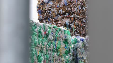 Stacks-of-crushed-plastic-bottles-for-recycling-behind-fence,-boom-down-view