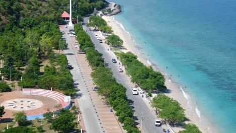 Aerial-view-of-people-visiting-popular-Cristo-Rei-white-sandy-beach-with-turquoise-ocean-water-in-capital-Dili,-Timor-Leste,-Southeast-Asia