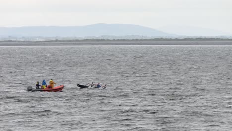 Orange-support-boat-follows-currach-paddlers-assisting-in-their-safety