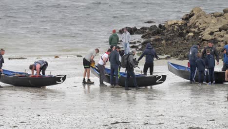 Group-of-competitor-athletes-stand-around-currach-boats-in-galway-ireland