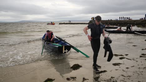 Man-pulls-currach-boat-onshore-at-ladies-beach,-galway-ireland