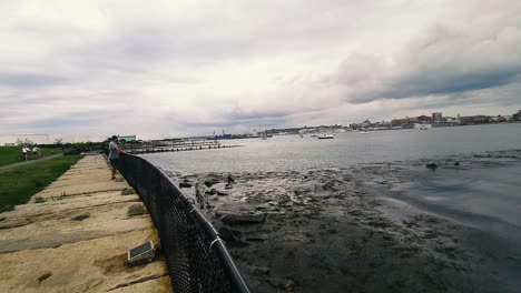 Tourists-looking-out-over-Casco-Bay-at-low-tide-with-dark-clouds
