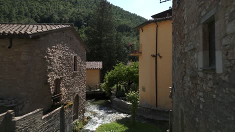 Luftflug-über-Wasser,-Das-Unter-Einer-Holzbrücke-In-Rasiglia,-Einem-Kleinen-Dorf-In-Der-Provinz-Perugia,-Vorbeifließt