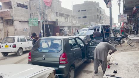 Shot-of-mechanics-repairing-a-car-in-the-car-repairing-market,-Saddar-in-Karachi,-Pakistan-at-daytime