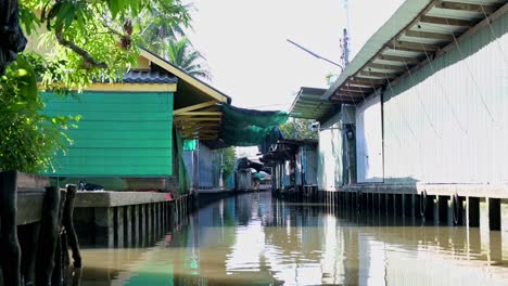 Paddling-a-wooden-boat-in-the-canal-of-Damoen-Saduak-Floating-Market,-Thailand