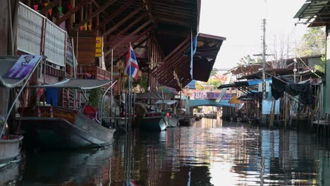 A-boatman-steering-his-wooden-boat-in-the-canal-of-Damoen-Saduak-Floating-Market,-Thailand