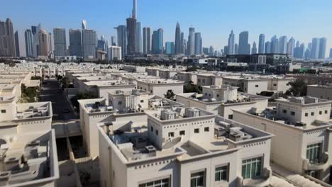 Aerial-tilt-up-shot-showing-man-walking-on-rooftop-enjoying-view-over-Dubai-City-with-Skyline,-UAE
