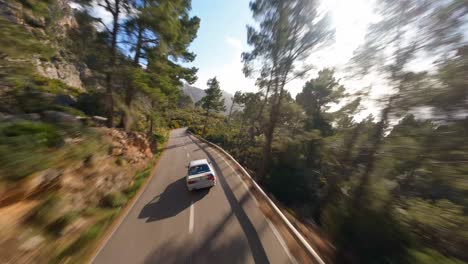 Antena-Panorámica-De-FPV-Siguiendo-Un-BMW-Conduciendo-Por-Una-Carretera-Pintoresca-En-La-Costa-Mediterránea-De-Mallorca