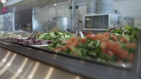 Vitrine-In-Einem-Café-Voller-Frisch-Zubereiteter-Salate,-Im-Hintergrund-Kochgeräte