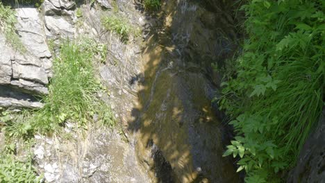 Top-Down-View-of-Small-Swiss-Alps-Stream-in-Summer-Flowing-Through-Rocks-with-Greenery