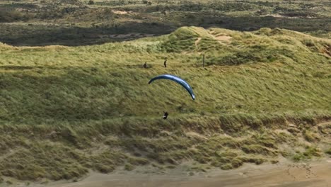 Extreme-Paragliding,-Sunny-Day-Long-Shadows,-Wide-Aerial-Tracking-Shot-Costal,-Langevelderslag-Beach,-Netherlands