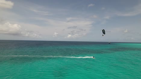 Atemberaubende-Luftaufnahmen-Von-Kitesurfern,-Die-In-Der-Nähe-Einer-Kleinen-Insel-Im-Karibischen-Meer-Segeln