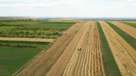 Aerial-drone-shot-flying-high-over-modern-harvest-combine-harvesting-wheat-on-the-yellow-ripe-wheat-field-on-a-cloudy-day