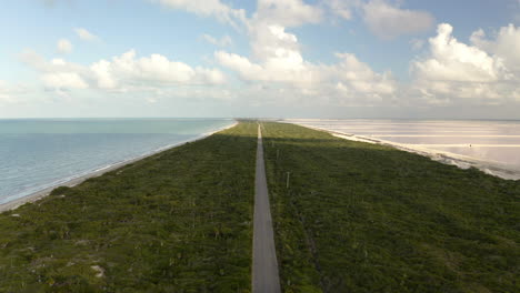 Long-straight-road-on-grassy-isthmus-between-sea-and-salt-ponds