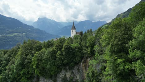 Aerial-panning-shot-of-Roman-Catholic-Church-in-Amden-with-Swiss-Alpine-backdrop