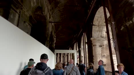 POV-Walking-With-Tourist-Tour-Group-Inside-Corridors-With-Arches-At-The-Colosseum-In-Rome