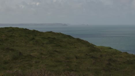 Wide-shot-of-sea-and-cliffs-with-Port-Isaac-in-background-and-Meadow-in-foreground