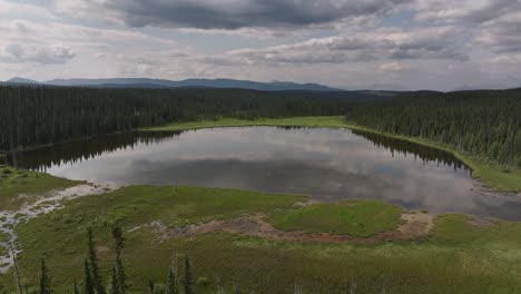 A-drone-circles-a-tranquil-pond-in-the-boreal-forest-of-Alberta,-Canada