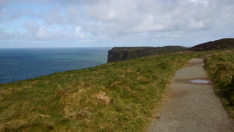 Extra-Wide-shot-of-coastal-path-looking-at-Tintagel-cliffs-in-background,-from-Lower-Penhallic-Tregatta