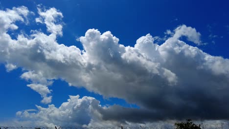 Timelapse-of-passing-clouds-with-dark-thundercloud-at-edge-with-blue-sky-behind-on-summer-day-before-summer-thunderstorm