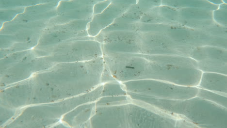 Cinematic-slow-motion-shot-of-water-caustics-with-sandy-sea-floor-beneath,-4K