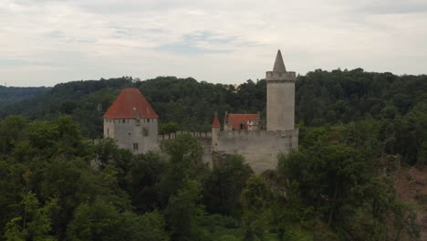 Medieval-Kokorin-castle-towering-above-hilly-forest-landscape,-Czechia