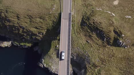 Tracking-drone-shot-of-a-car-crossing-the-Scalpay-island-bridge,-near-the-Isle-of-Harris-on-the-Outer-Hebrides-of-Scotland
