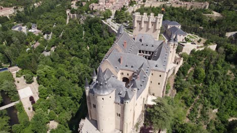 Aerial-Overhead-View-Of-Alcazar-of-Segovia-Castle,-Slow-Tilt-Up-To-Reveal-Cityscape-In-Background