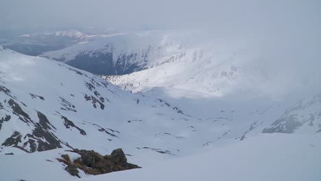 Piernas-Y-Pies-De-Escalador-Descansando-En-El-Borde-Del-Pico-De-Una-Montaña-Cubierta-De-Nieve.
